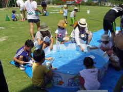 外のプールで水遊びをする子どもたち